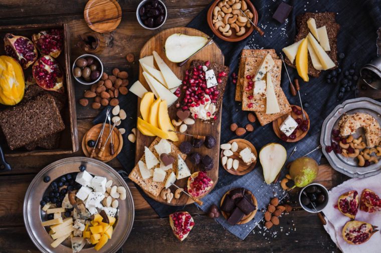 Appetizers table. Cheese variety board with tropical fruits, nuts, and wine. Family party table. Different cheese and fruits.