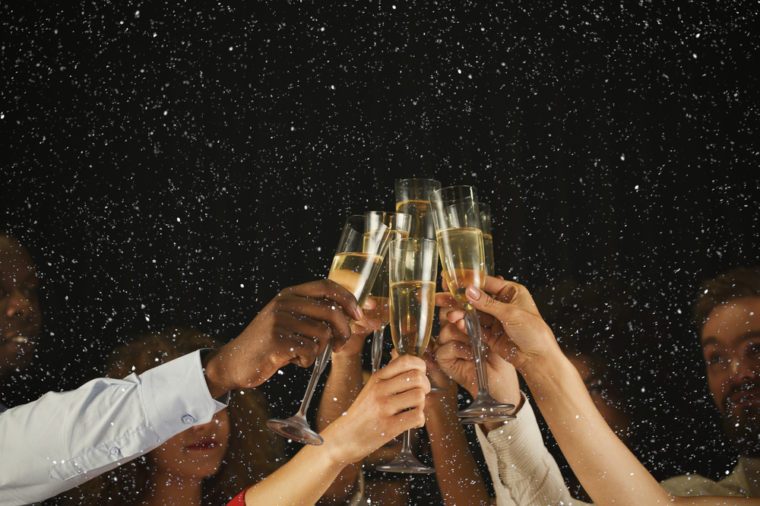 Christmas party time. Young people toasting with champagne flutes. Multiethnic friends congratulating each other with new year. Celebration and nightlife concept, holiday background, selective focus
