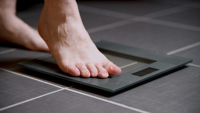 Male feet on glass scales, men's diet, body weight, close up, stepping on digital scale, sport and lifestyle concept