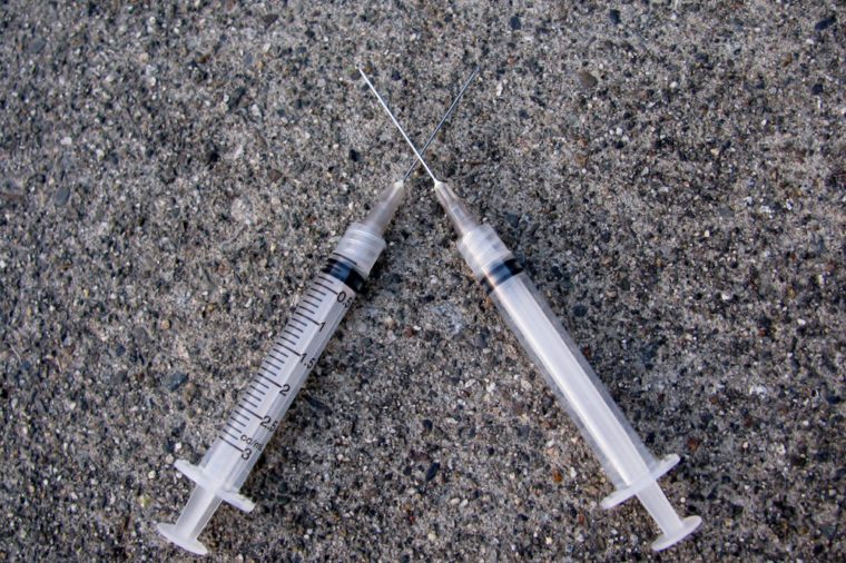 Two crossed syringes on concrete floor