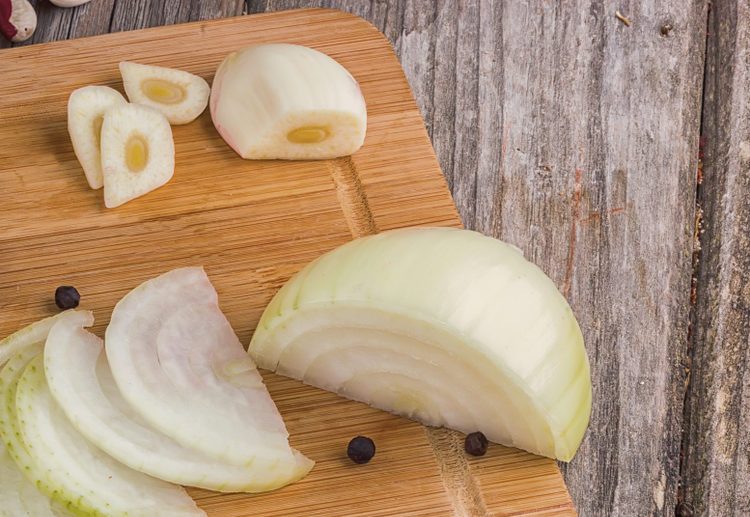 cut onion and garlic, black pepper on a wooden board