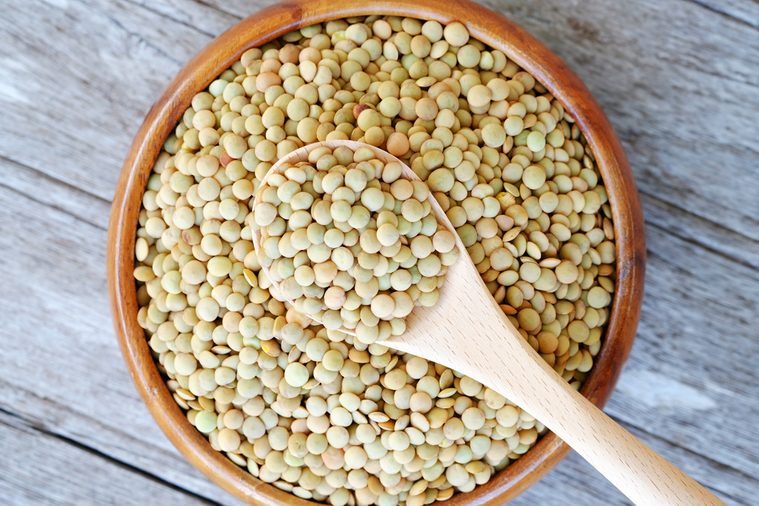 Top view of Lentils in a spoon and on wooden background. Natural organic lentils for healthy food and copy space.