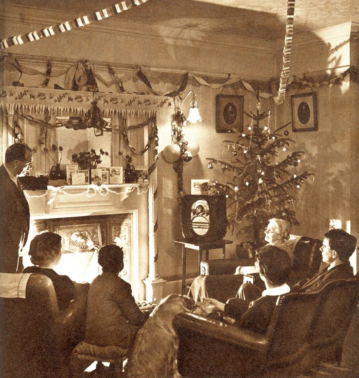 Mandatory Credit: Photo by Historia/Shutterstock (9831785a) A 1950s Family Sit Around the Fire at Christmas Time Listening to A Wireless Broadcast Streamers and Paper Chains Hang From the Ceiling and A Rather Mean Looking Christmas Tree Stands in the Corner. . Photograph by Sketch Special Photographer, Harold White, the Sketch, 31 December 1952 Christmas 1952 by Harold White, 1952
