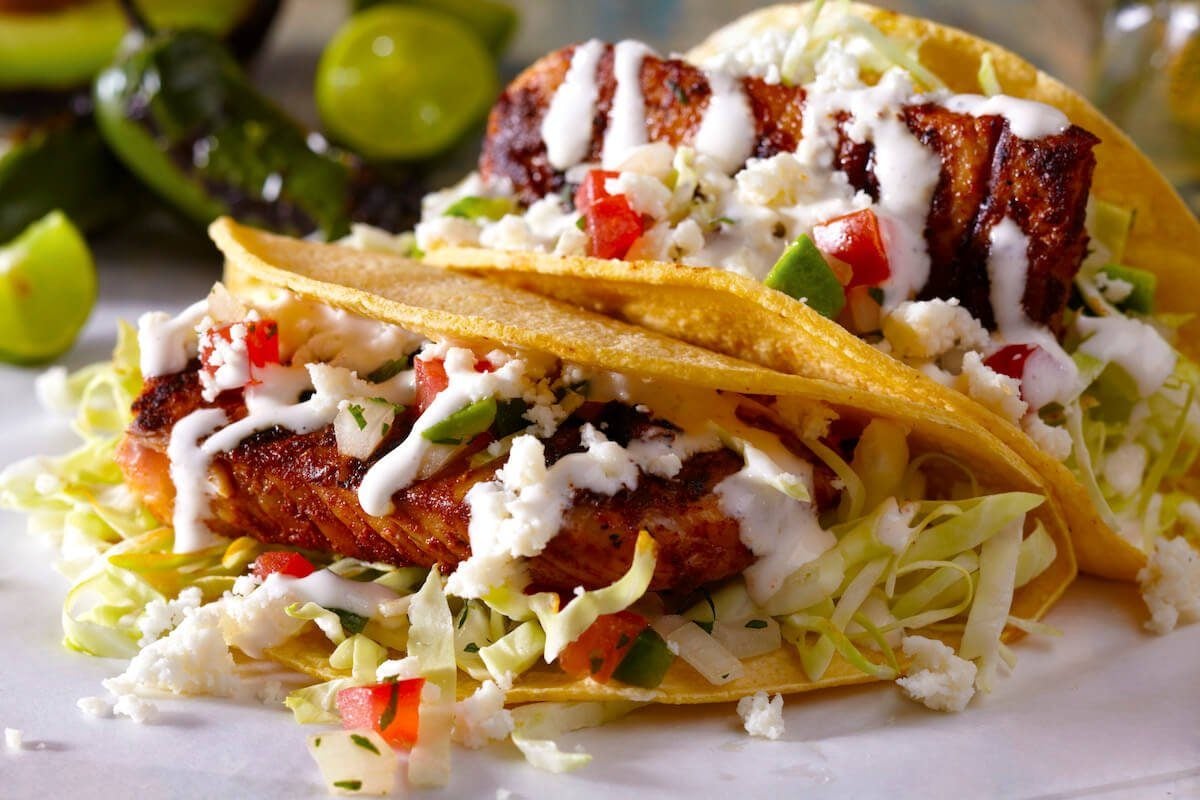 Grilled fish tacos with diced avocado and crema