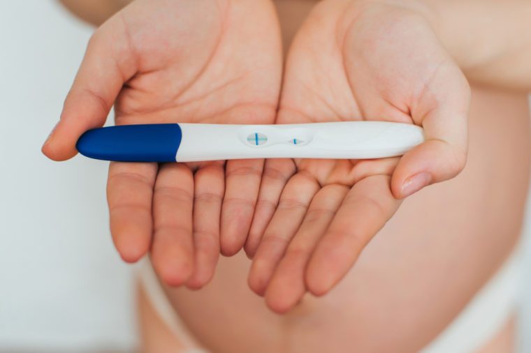 pregnancy test in the hands of a girl with a positive result close up