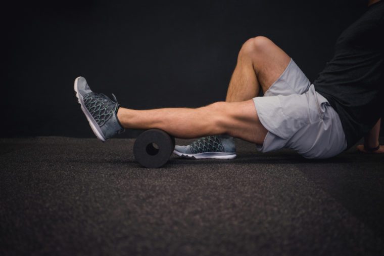Athletic man using a foam roller to relieve sore muscles after a workout. 