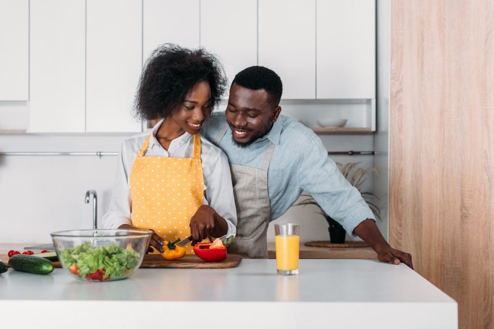 African american couple in aprons standing at table and cooking