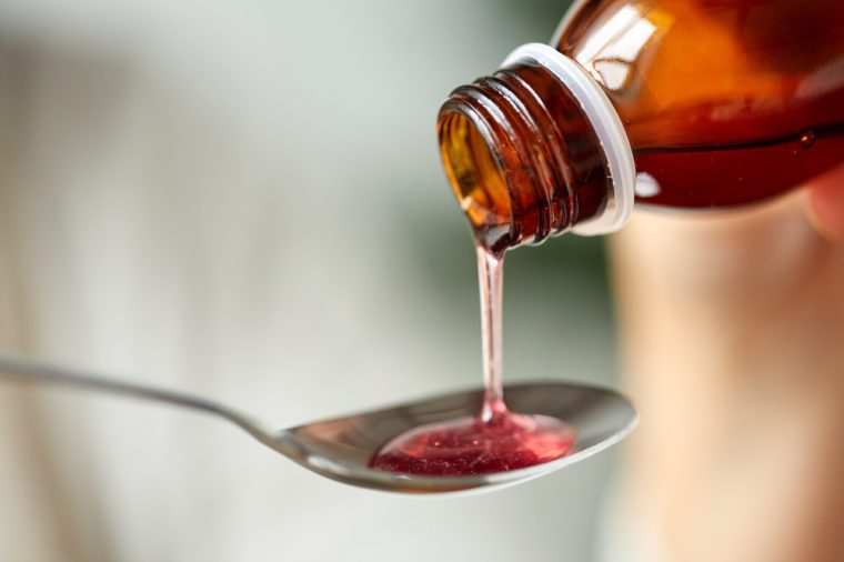 healthcare, treatment and medicine concept - bottle of medication or antipyretic syrup and spoon