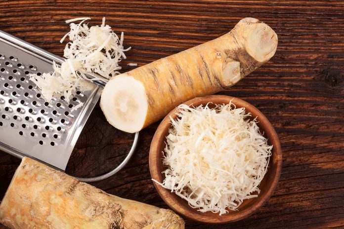 Fresh grated Horseradish roots on wooden table. Rustic style from above. 