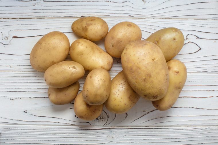 Young potatoes on white wooden background, view from above