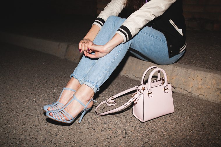 young stylish hipster woman, swag outfit, jeans, cool accessories, sitting on ground, pink purse, legs close up, details, shoes