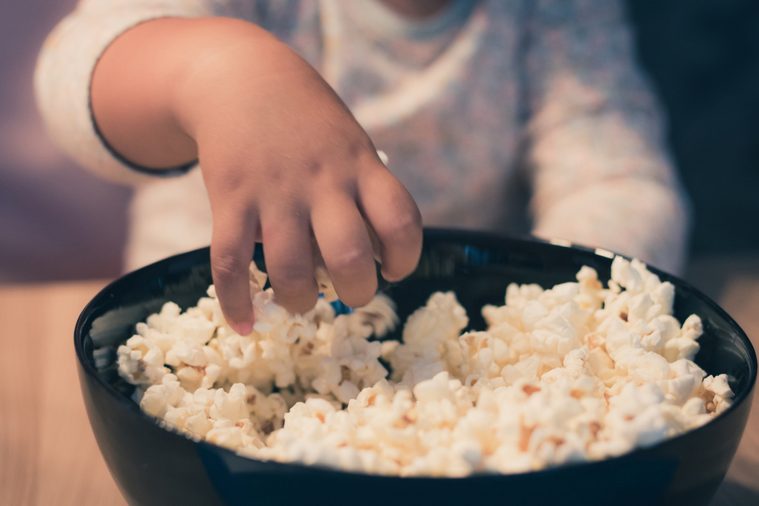Close up of small kid eating popcorn.
