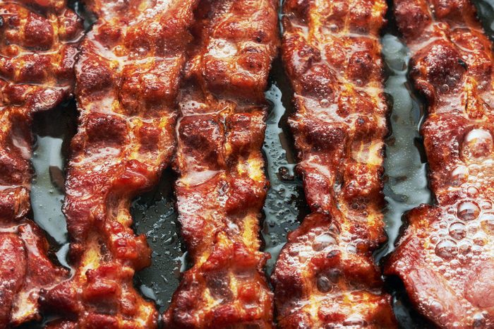  Bacon slice being cooked in frying pan. Close up. 