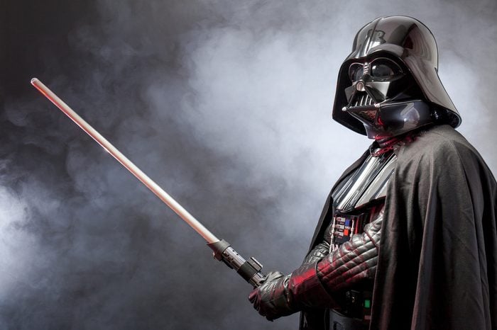 SAN BENEDETTO DEL TRONTO, ITALY. MAY 16, 2015. Portrait of Darth Vader costume replica with his sword . Lord Fener is a fictional character of Star Wars saga. Black background with smoke