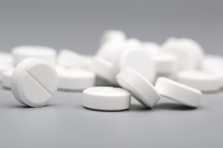 Heap of white round pills medical on a gray background