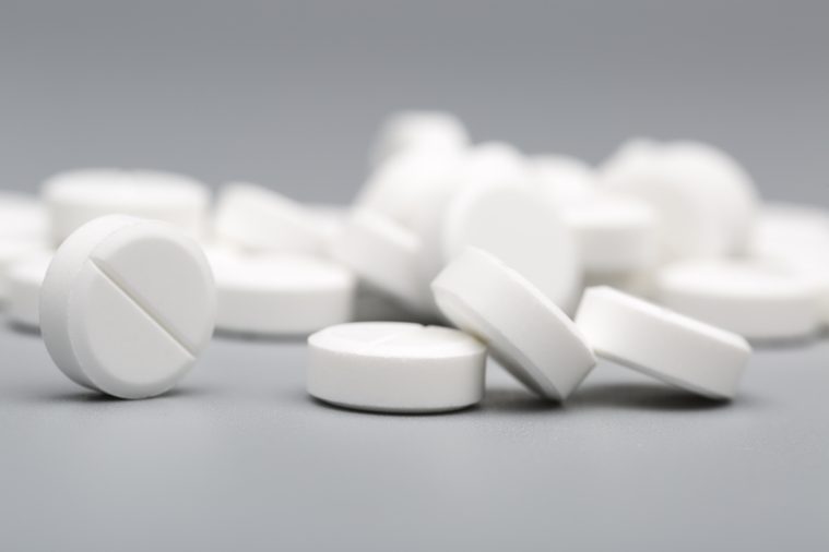 Heap of white round pills medical on a gray background