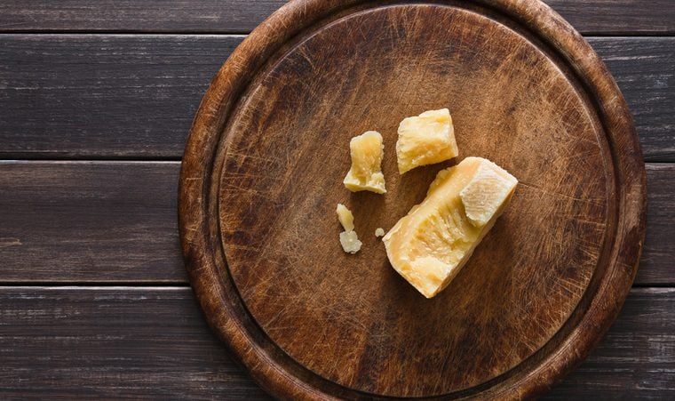 Cheese delikatessen pieces on rustic wood. Wooden desk with parmesan cuts, top view image with copy space