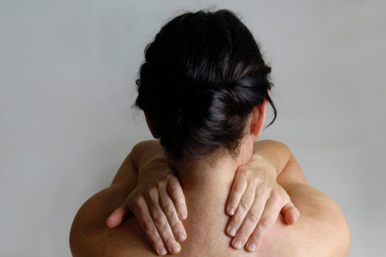 Nude woman with a back pain