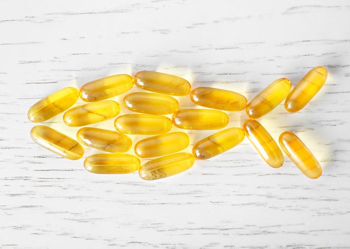 Omega 3 capsules in shape of fish on wooden background