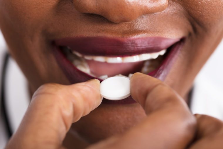 Close-up Of An African Woman Taking Medicine Pill