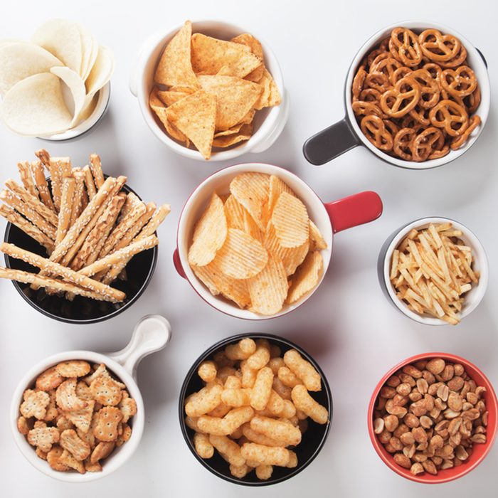 Potato chips,pretzels, roasted peanuts and other salty snacks over white background