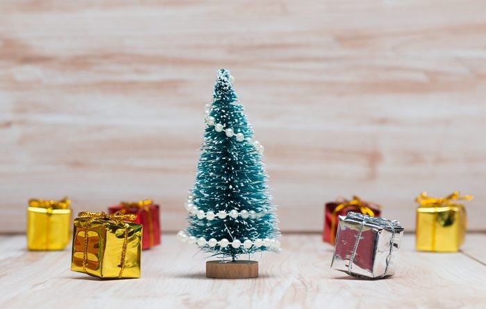 little Christmas tree and gifts on wooden background