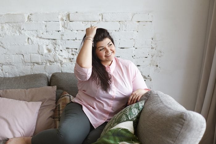Beauty, obesity and body positive movement concept. Indoor shot of gorgeous attractive young overweight Caucasian brunette woman with big breast and hips enjoying good sunny day, resting on couch