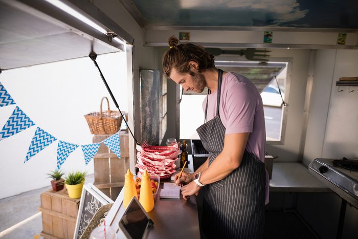 Waiter writing in notepad at food truck counter