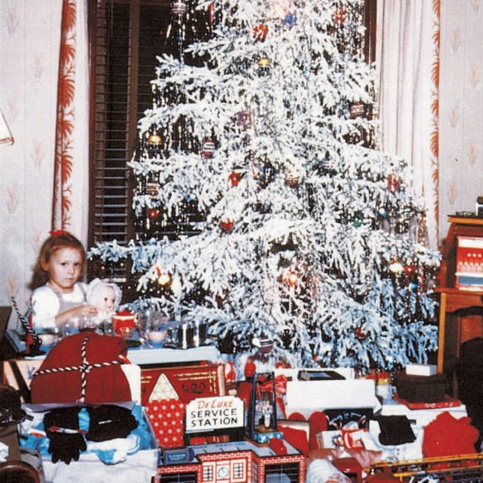 Girl and a boy sitting among opened presents under a Christmas tree