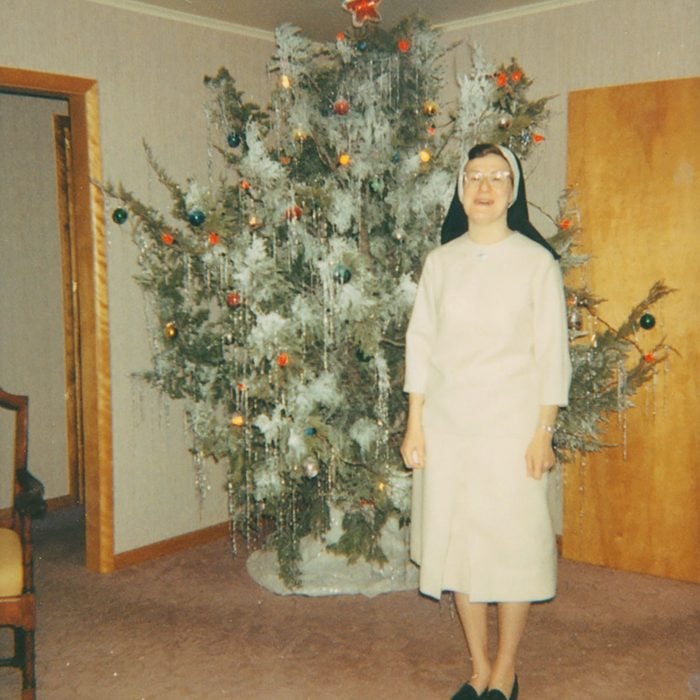 Woman standing in front of a decked out, live Christmas tree