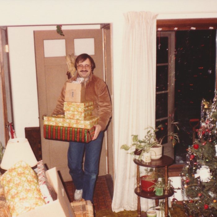 Man coming in through the front door with a present in hand