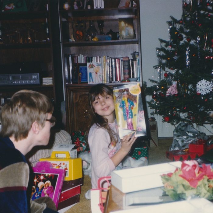 Young girl excitedly holds up Barbie she got for Christmas