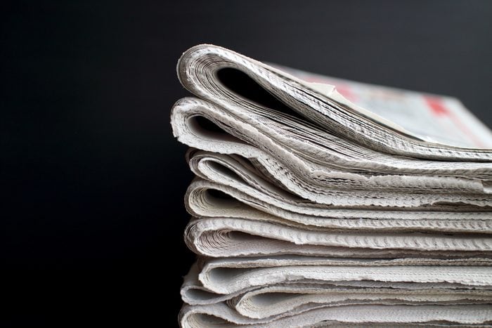 Stack of folded newspapers in front of a black background with copy space