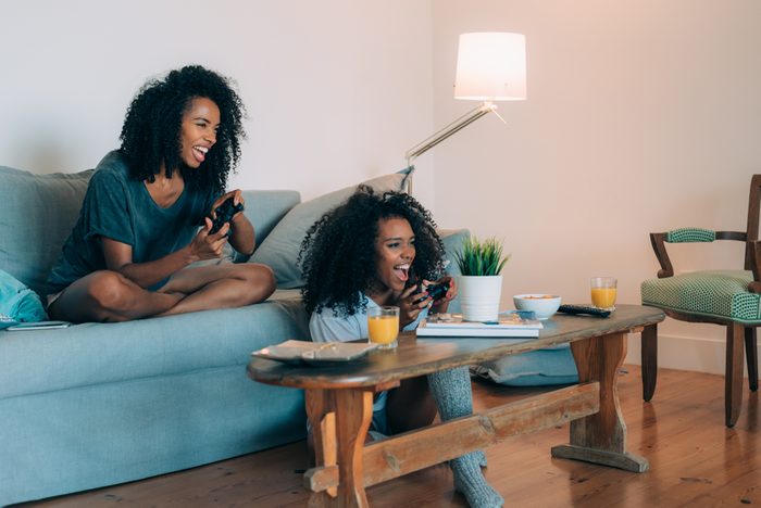 Happy young two black women sitting in the couch playing video games