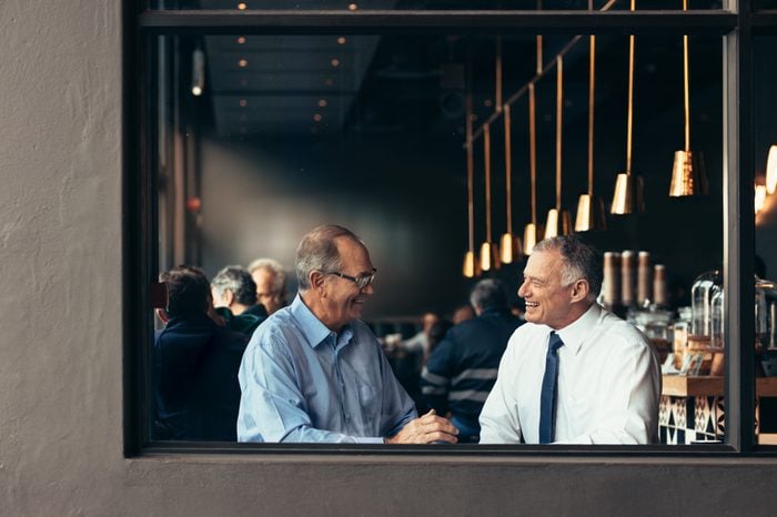 Two business partners having a casual discussion at cafe after work. Happy senior businessmen talking and smiling at a restaurant.