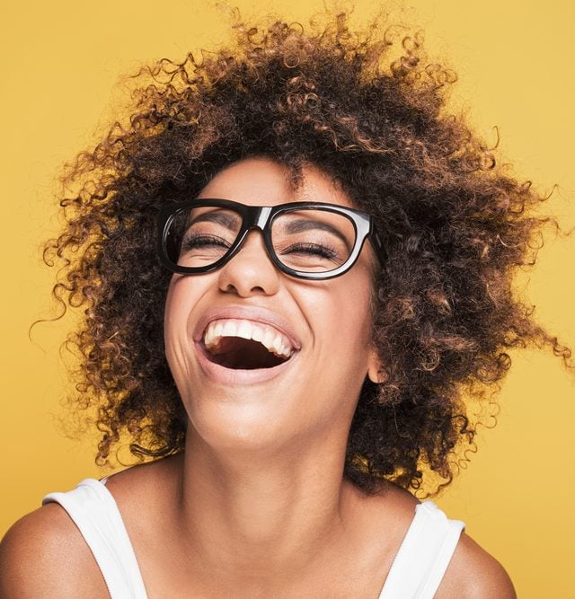 Young beautiful african american girl with an afro hairstyle. Attractive girl wearing eyeglasses. Portrait. Yellow background.