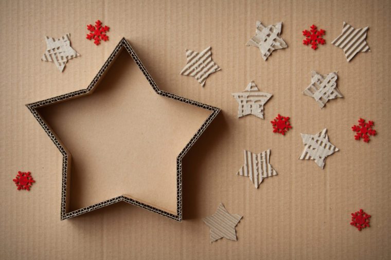 Christmas gift box in the shape of a star, surrounded by decorations, on cardboard background