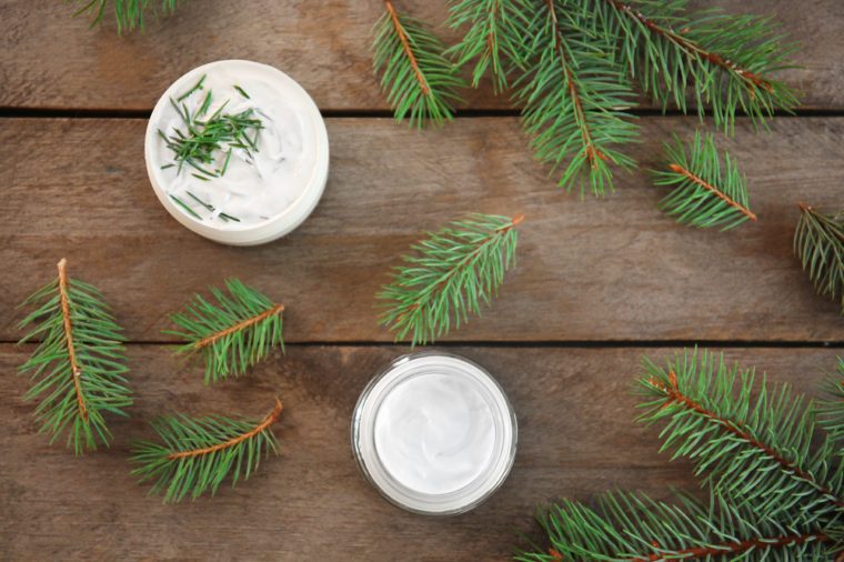 Cream and pine branches on wooden background