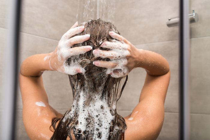 Rear view of girl washing hair with shampoo