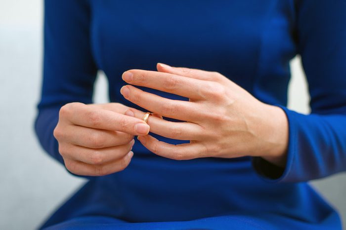 Divorce concept. Woman taking off wedding ring.