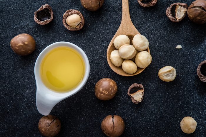  Macadamia Nut Oil and peeled macadamia nut on black stone , ï»¿use for Healthy Skin and Hair and Natural Healing Oil Treatment , overhead and top view
