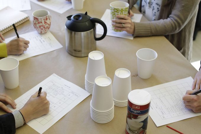 Taste testers taking notes surrounded by pots of coffee and cups