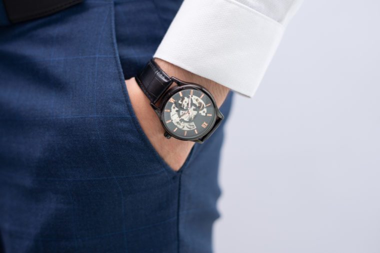 Close-up of male hand in pocket with modern elegant wristwatch. Caucasian businessman wearing stylish watch. Fashion and punctuality concept