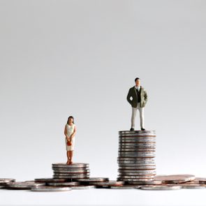 The concept of gender gap between employment and promotion. Miniature people standing on a pile of coins.