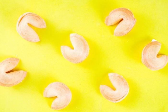 Chinese fortune cookie with prediction on bright yellow background top view copy space