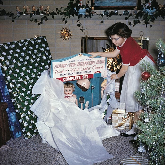 Young girl unwrapping a doll for Christmas