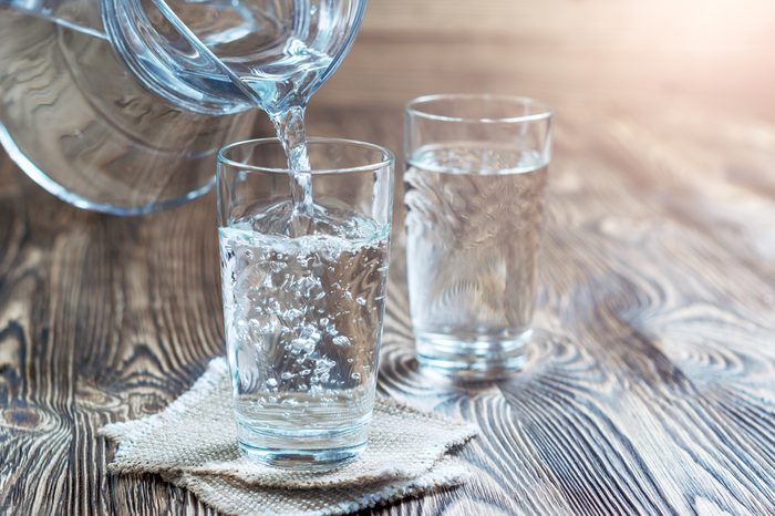 Glass of water on a wooden table. Water was poured into the beaker. Selective focus. Shallow DOF. With lighting effects. With copy space