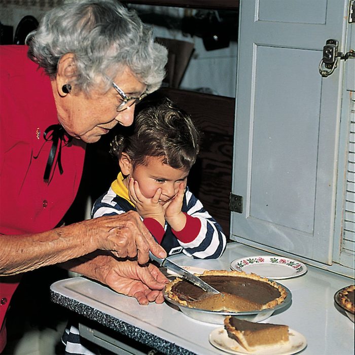 Grandma cutting a slice of pie for her grandchild