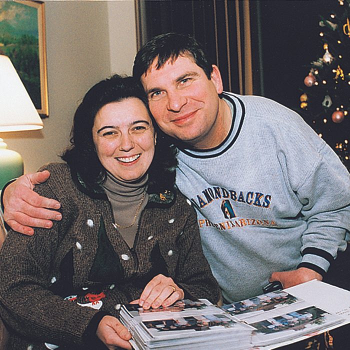 Man and woman hugging over a photo book of Christmas memories