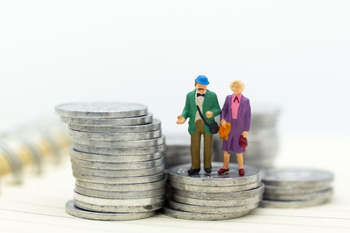 Miniature people, adult couple figure standing on top of stack coins . Image use for background retirement planning, Life insurance concept.